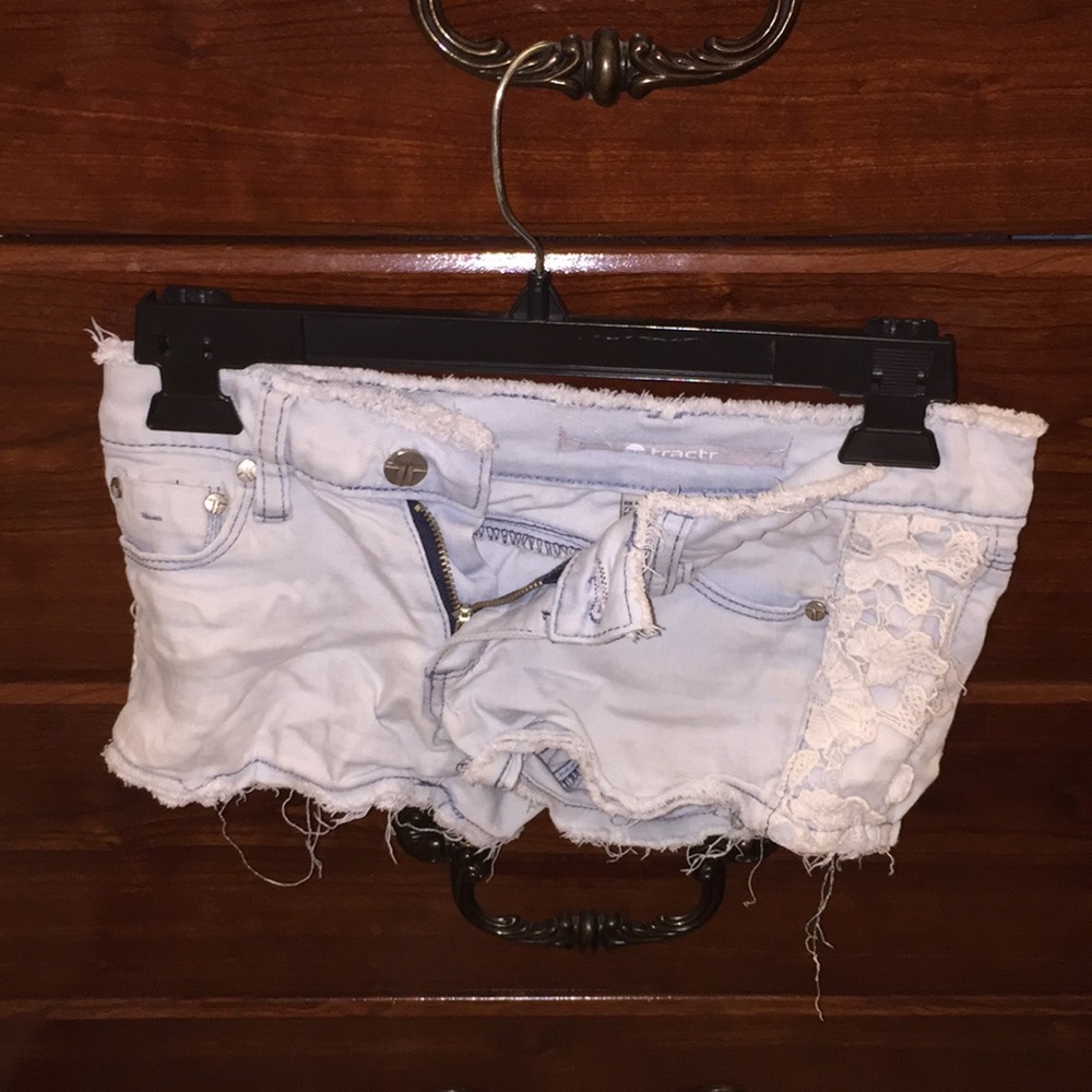 Light wash denim shorts with lace flower trimming.